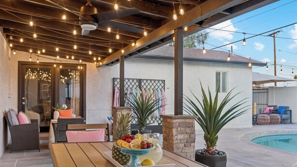 An outdoor patio with a wooden table, a fruit bowl, and potted plants.