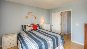 A bedroom with a bed, a nightstand, a lamp, and a door.