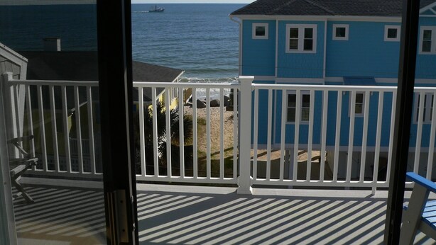 A balcony with a view of the ocean and a blue building.