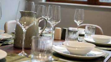 A dining table set with clear glassware, white plates, and a pitcher.
