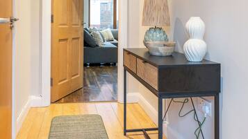 A hallway with a wooden door, a console table with a lamp, and a mirror.