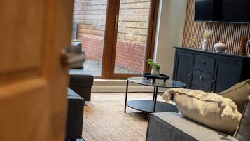 A living room with a sofa, a coffee table, and a TV mounted on the wall.