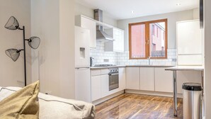 Una cocina moderna con gabinetes blancos, una estufa de acero inoxidable y un ventanal con marcos de madera.