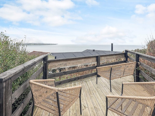 A wooden deck with wicker chairs overlooking a body of water.