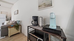 A modern kitchen with a coffee station, a refrigerator, and a dining area with a sofa and a plant. - The Seapearl at UTC-1/1 Guest Suite (Sarasota)