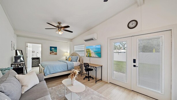 A bedroom with a bed, a desk, a chair, a ceiling fan, and a large window with blinds. - The Seapearl at UTC-1/1 Guest Suite (Sarasota)