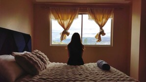 A bedroom with a bed, a window with curtains, and a view of the outdoors. - Incredible apartment with private cinema (pet friendly) (Riobamba)