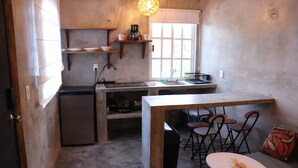 A compact kitchen with a built-in refrigerator, a coffee maker, and a window providing natural light.