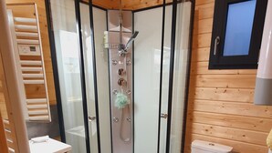 A compact, wooden cabin bathroom with a glass-enclosed shower, a toilet, and a sink. - Chalet with terrace and garden 5 minutes from the village, near lake and ski resorts (La Tour-d'Auvergne)