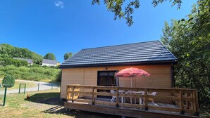 A small wooden cabin with a deck and outdoor seating area, surrounded by greenery. - Chalet with terrace and garden 5 minutes from the village, near lake and ski resorts (La Tour-d'Auvergne)