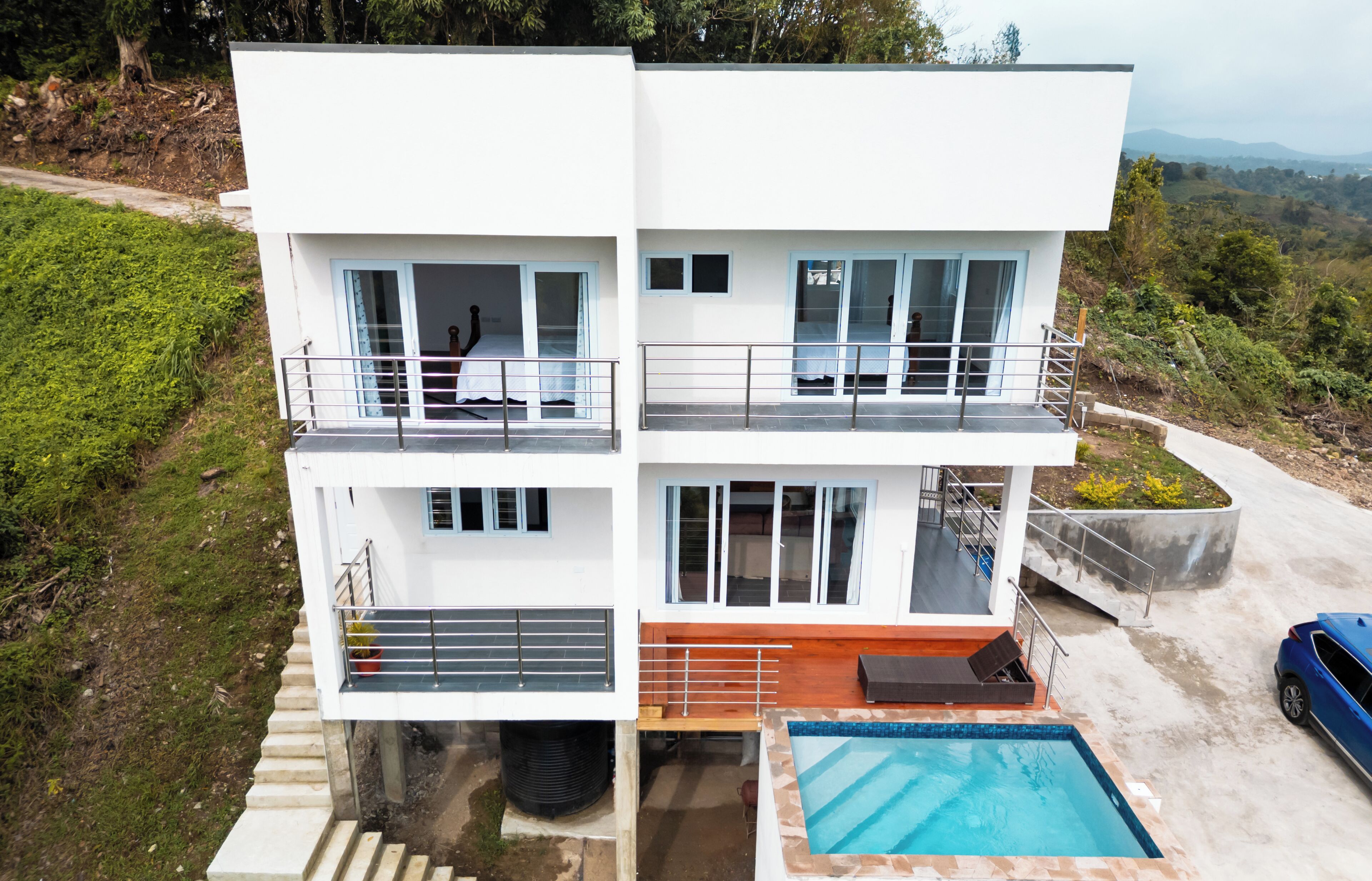 Une maison moderne à deux étages, dotée d’une piscine, d’un balcon et offrant une vue sur le paysage environnant.