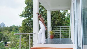 A balcony with a potted plant, a metal railing, and a view of greenery and mountains in the background. - Majestic Dream Villas (Choiseul)