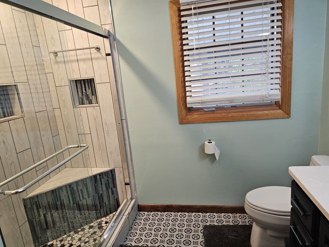 Et badeværelse med bruser, toilet og håndvask.