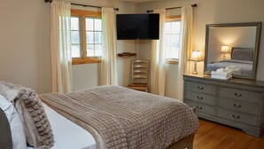 Un dormitorio con cama, cómoda, televisor y espejo.