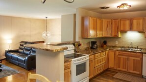 Cocina compacta con armarios de madera, horno empotrado y encimera con cafetera.