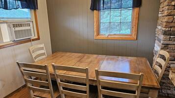 Un coin repas avec une table et des chaises en bois, un lustre et un mur décoratif en pierre.