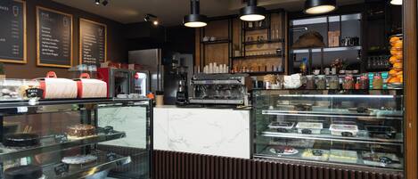 Una vitrina de panadería con diversos productos horneados y una máquina de café al fondo.