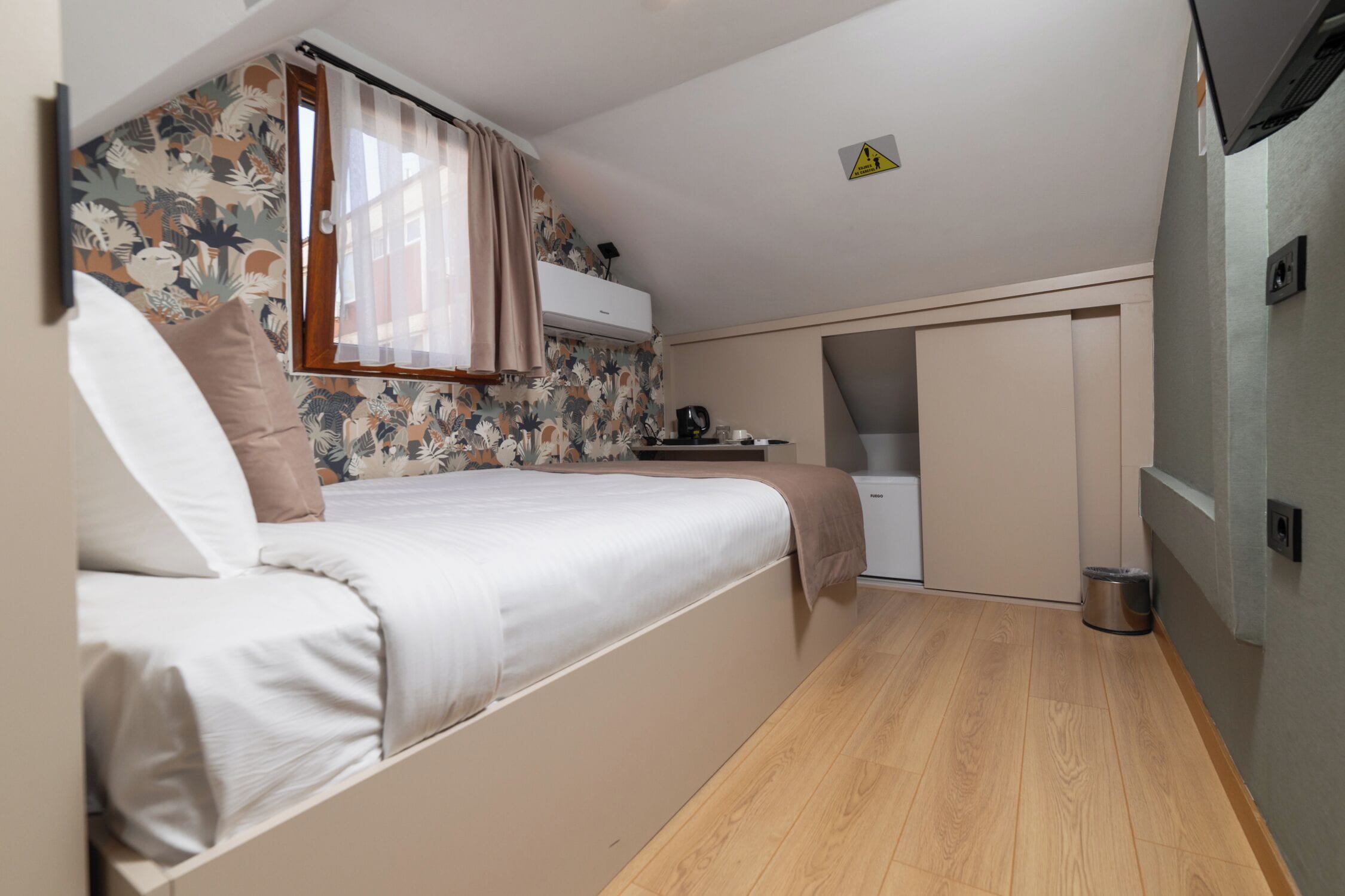 A compact room with a bed, a small kitchenette, and a sliding door closet.