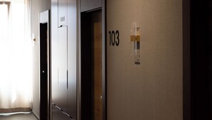 A hallway with three doors, one of which is open, revealing a room. The number 103 is visible on the wall. - Hotel Ma Belle (Pristina)