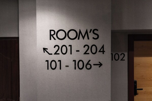 Letrero en la pared que indica los números de habitación 201 a 204 y 101 a 106 de un hotel.