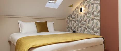 A bedroom with a skylight, a bed with white and mustard bedding, and a patterned wall.
