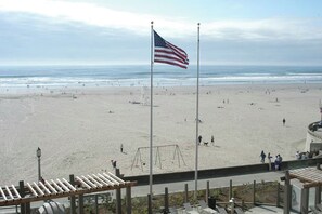 A beach with a flagpole, a swing set, and a view of the ocean. - Charming 1-bedroom unit in resort with fitness room in Seaside next to boardwalk (Seaside)
