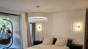 A bedroom with a large bed, a hanging chair by the window, and a chandelier. - Apartment Henri Martin, Trocadero, luxury and chic, Eiffel Tower view (Paris)