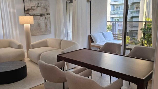 A modern living room with a wooden dining table, beige sofas, and a floor lamp. - Apartment Henri Martin, Trocadero, luxury and chic, Eiffel Tower view (Paris)