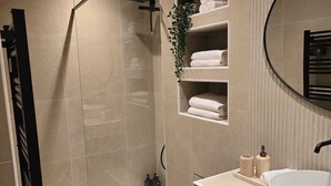 A modern bathroom with a walk-in shower, a large sink, and a built-in shelf with towels. - Apartment Henri Martin, Trocadero, luxury and chic, Eiffel Tower view (Paris)