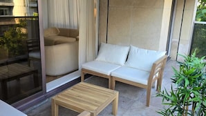 A modern outdoor seating area with a sofa, two wooden chairs, and a small table. - Apartment Henri Martin, Trocadero, luxury and chic, Eiffel Tower view (Paris)