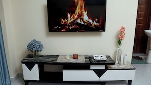Una sala de estar moderna con un televisor de pantalla plana montado en la pared mostrando un fuego.