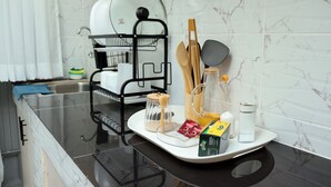 Una encimera de cocina con un escurreplatos, utensilios y una cafetera.