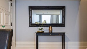 A dark wooden console table with a mirror above it, flanked by two gold-toned handles.