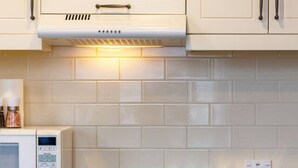 A kitchen with a built-in microwave, oven, and a countertop with jars.