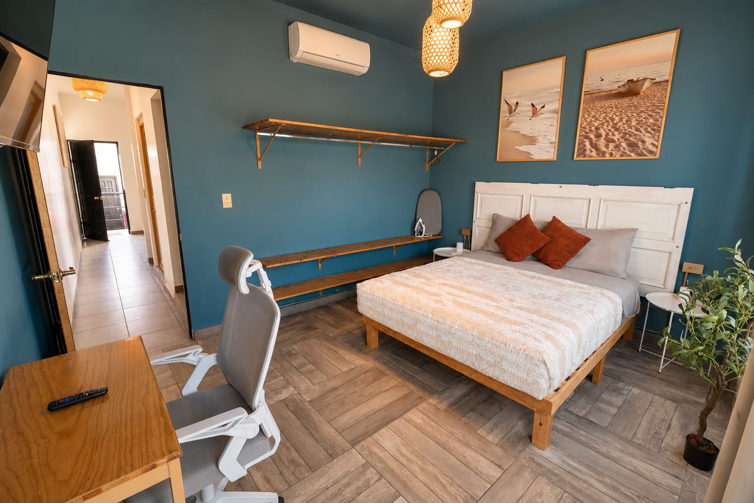 Un dormitorio con cama, mesita de noche, silla y escritorio con control remoto.