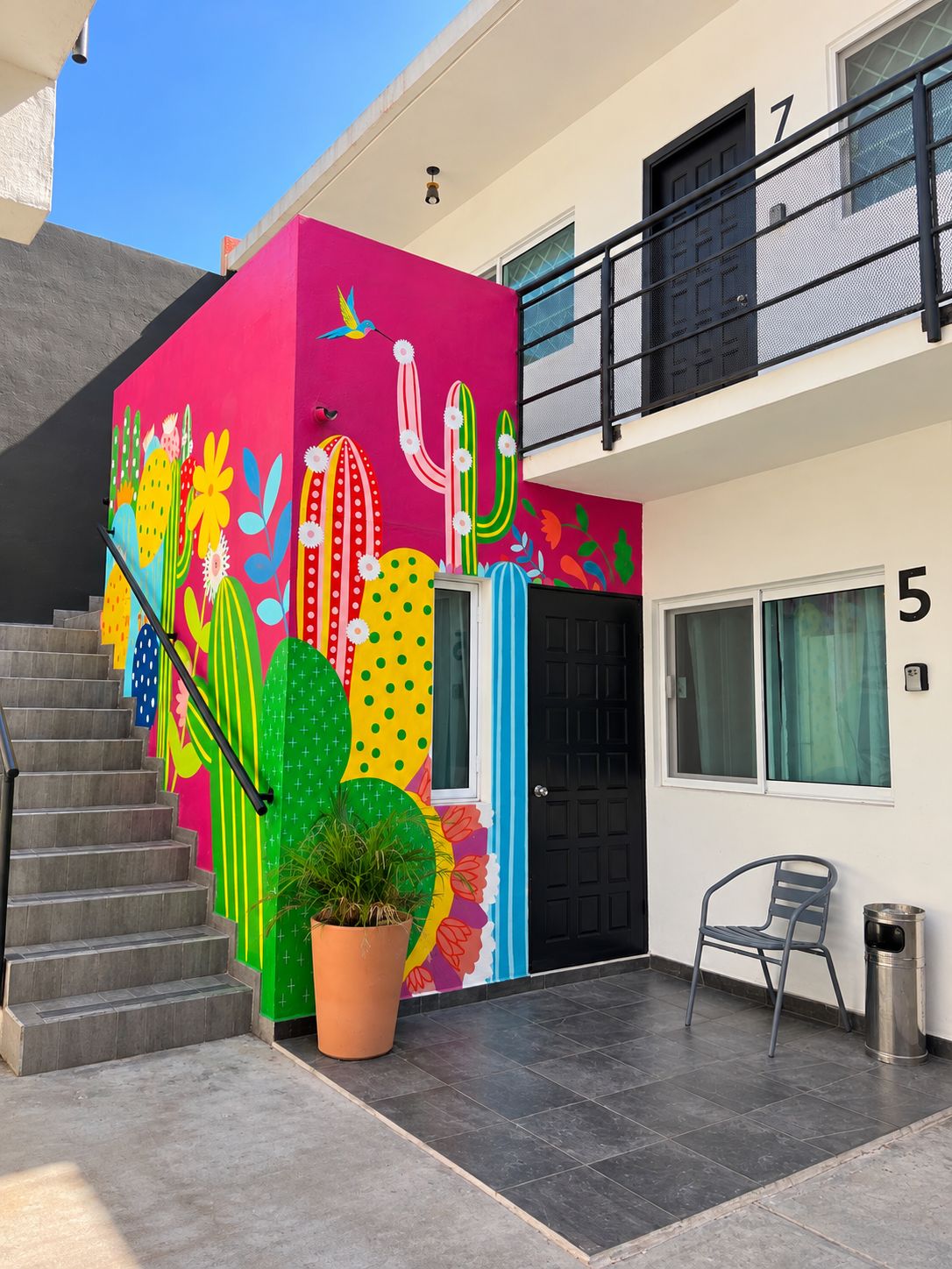Un edificio con un mural vibrante de cactus y flores en la pared exterior.