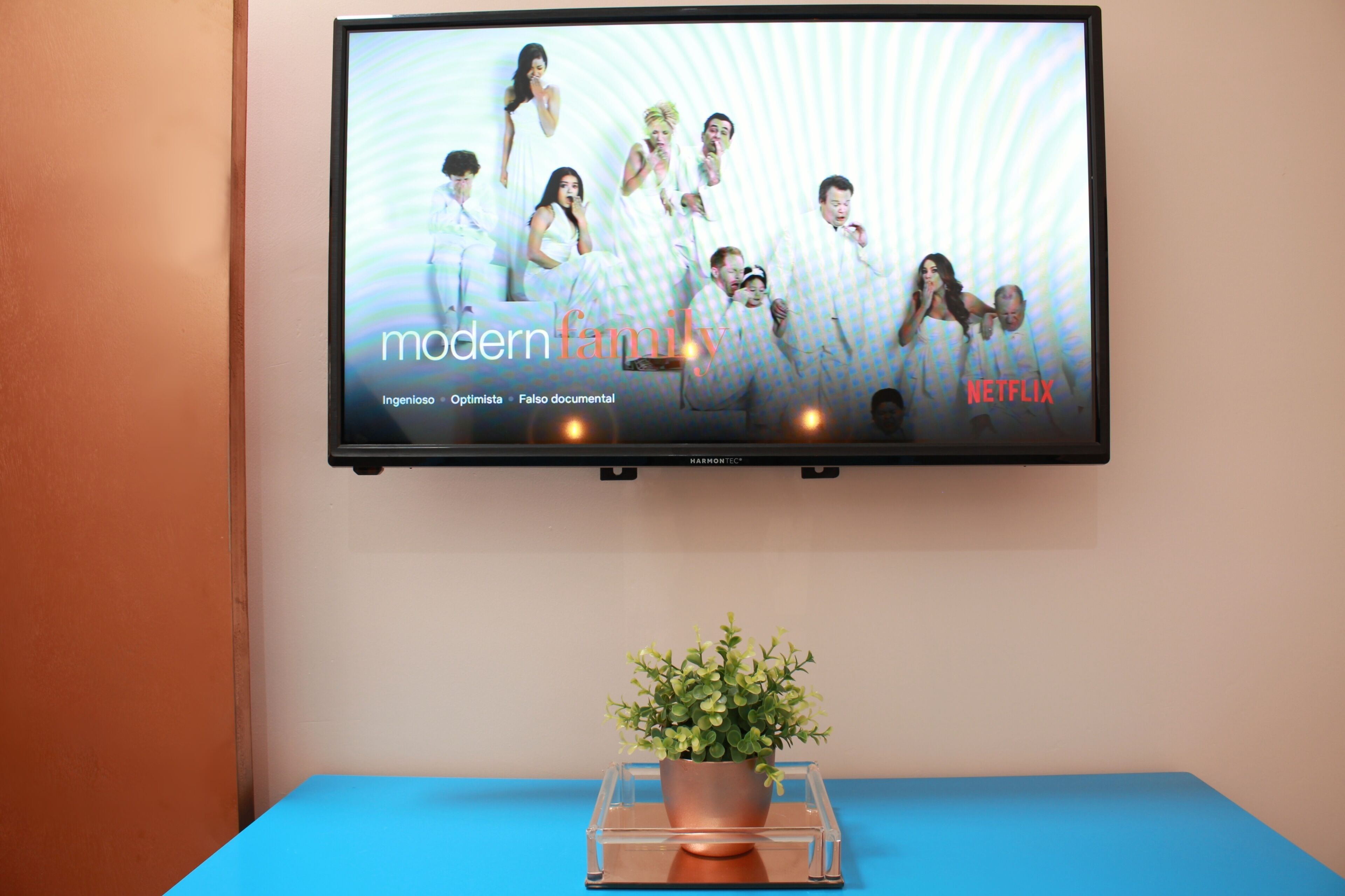 Televisor fixat a la paret que mostra un cartell promocional de 'Modern Family' a Netflix.