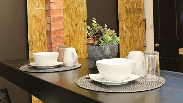 Un comedor moderno con una mesa larga, sillas negras y una planta en maceta.