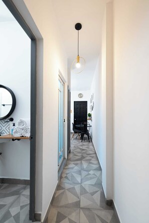 A hallway with geometric patterned flooring, a black door, a dining area with a table and chairs, and a pendant light. - Casa Navarro (La Paz)