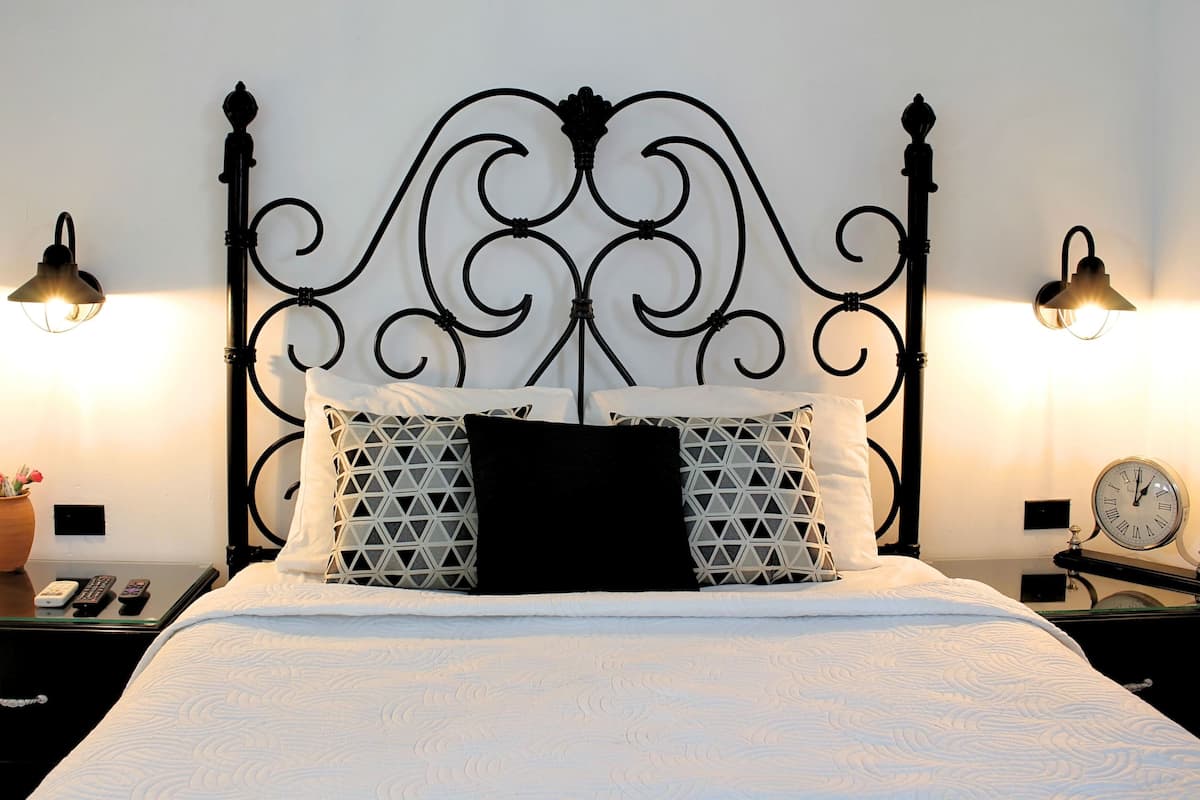 A neatly made bed with a black and white patterned pillow, a black headboard, and two bedside lamps.
