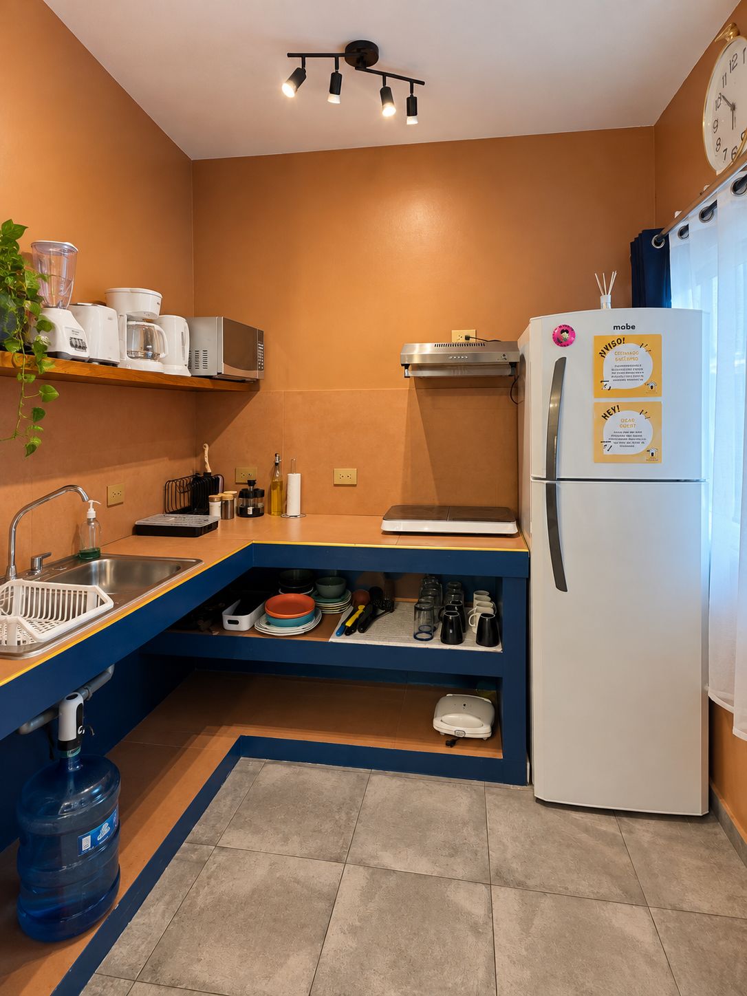 A compact kitchen with a built-in oven, a refrigerator with magnets, and a sink.