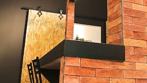 Un interior moderno con paredes de ladrillo visto, un revestimiento de listones de madera y una silla de metal negro.