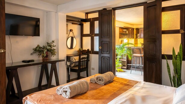 Habitación de hotel con cama, escritorio, silla, televisor y vistas a la cocina y el jardín.