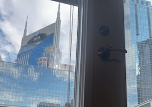 A view through a window with a door handle, reflecting a building with a blue facade and a Verizon logo.