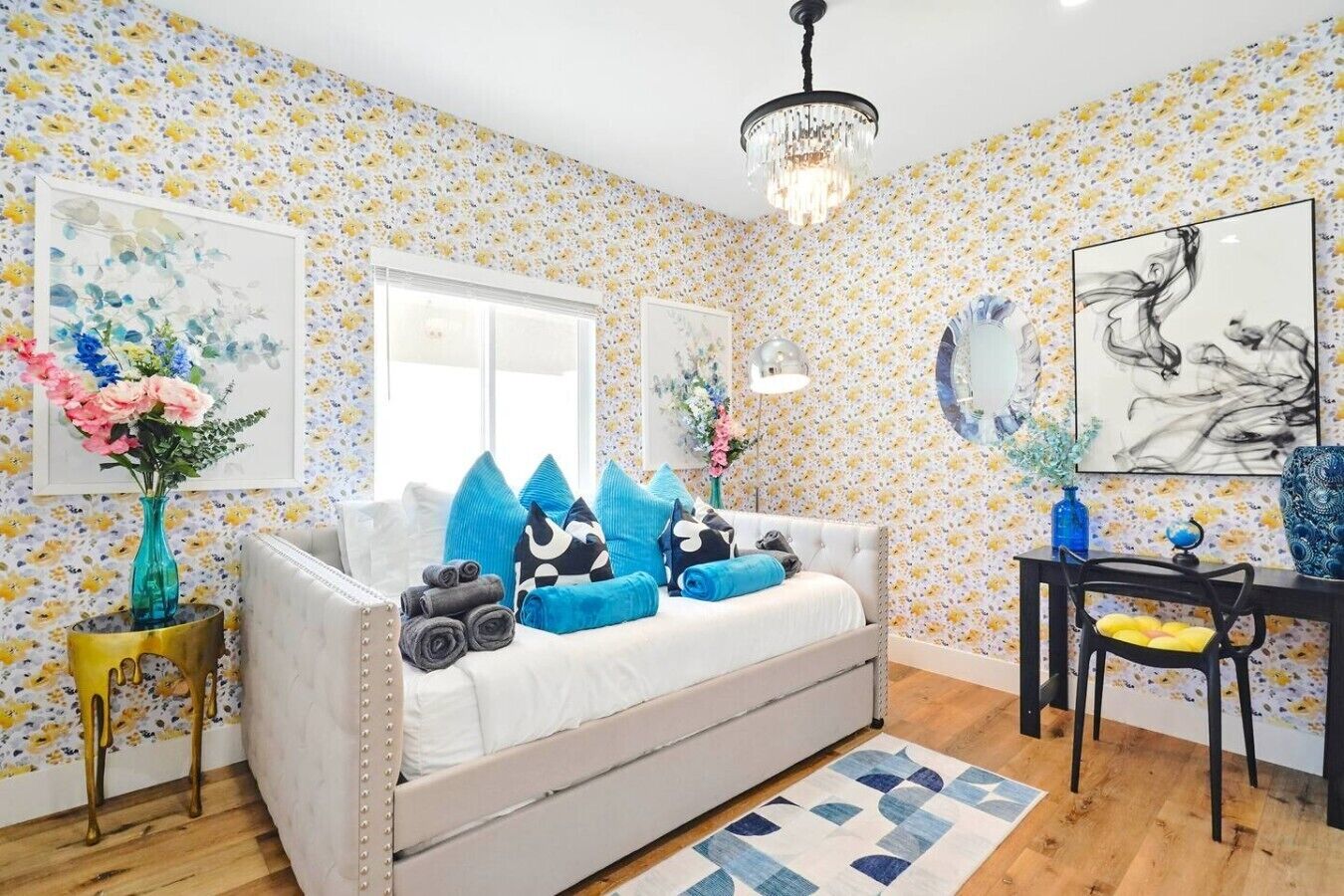 A room with a sofa, a chandelier, a mirror, and floral wallpaper.