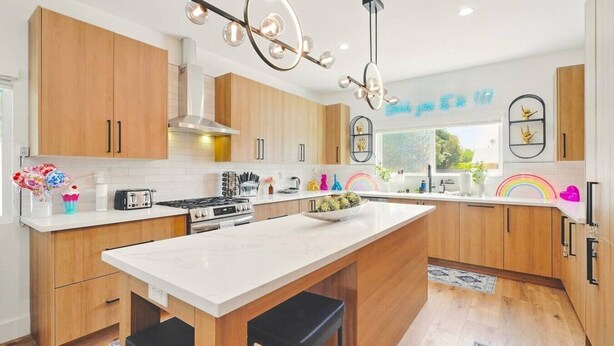 Una cocina moderna con armarios de madera, una isla central, estufa a gas e iluminación colgante.