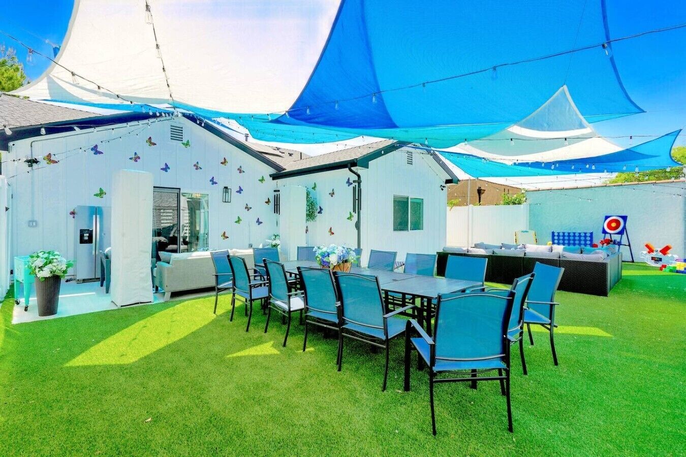 Une terrasse extérieure comprenant un espace repas, une cuisine et un espace de jeux avec un jeu de tir à la cible.