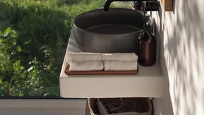 Un évier de cuisine avec une casserole, une bouilloire et une serviette posés sur une étagère.