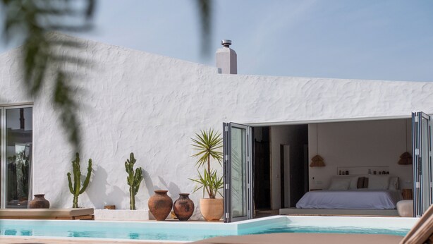 Une villa moderne dotée d’un espace de vie à aire ouverte, d’une piscine et d’une chambre comprenant un lit et une table de chevet.