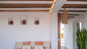 Un salon moderne avec un canapé blanc, des objets de poterie décoratifs et une grande plante en forme de cactus.